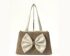 Untitled design (8) Neutral-toned structured handbag with double handles and a large ivory bow detail on the front, displayed on a minimalist background.